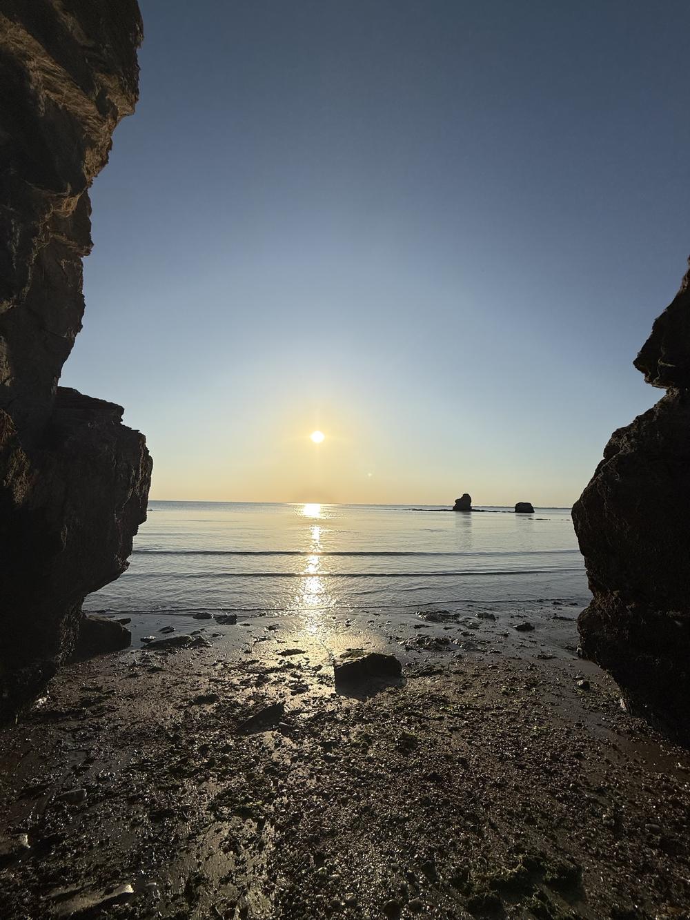 Coucher de soleil sur la mer, vu entre deux rochers